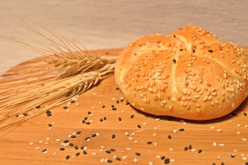 Top table with a fresh backed bun with  wheat and sesame ornament on wooden plate