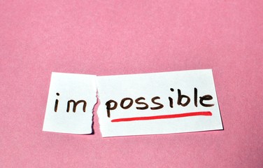 Concept of the word impossible written by hand and cut as possible, put on the pink table with copy text