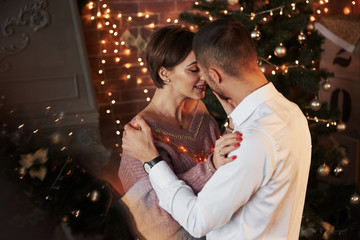 Reflection of the christmas tree. Closeness of the guy and girl in luxury wear that dancing and flirting