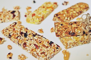Side view of sweet slices of healthy cereal bars with dried wheat and fruits on white table background