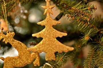 Golden Christmas decoration in the tree with soft bokeh. Close up, front view