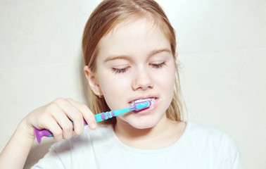 Close up of a child (kid) white European Caucasian girl washing the teeth with toothbrush