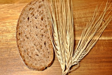 Top table of a slice of brown cereal healthy bread with dried wheat decoration on wooden table background