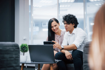 Haves a break time. Selfie of two smiling office workers in official clothes that sitting near silver laptop on table