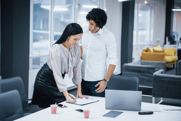 Obraz premium Windows and beds behind. Curly guy and brunette girl discusses the details of the contract in modern office