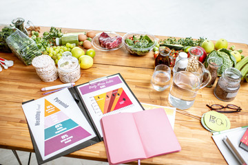 Nutritionists working place with drawings on the topic of healthy eating, empty notebook and different products on the table
