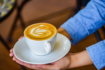 Hands holding coffee cup flower on coffee cup and woman finger.