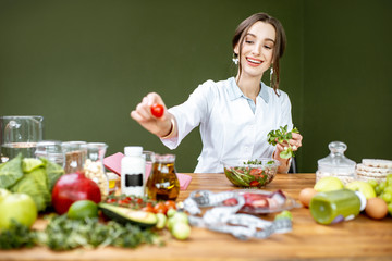 Woman dietitian working on a healthy diet making a salad with different raw products at the working...