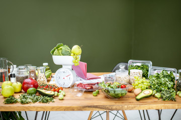 Nutritionists working place with variety of healthy raw food, weights and documents on a topic of...
