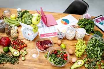 Nutritionists working place with variety of healthy raw food, weights and documents on a topic of healthy food on the table