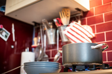 pot on gas stove with dishes on the side in red kitchen.