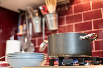 pot on gas stove with dishes on the side in red kitchen.