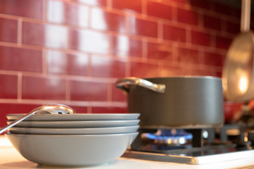 pot on gas stove with dishes on the side in red kitchen.