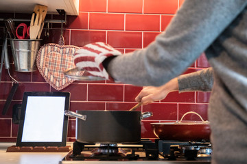 woman cooking while reading recipe on tablet