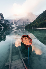 Stairs that goes into the water. Wooden boat on the crystal lake with majestic mountain behind