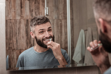 Handsome bearded man brushing his teeth in the morning