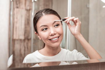 Dark-haired businesswoman using gel mascara for eyebrows