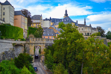 Fototapeta na wymiar View of a medieval gate or door in the wall of the old town of Luxembourg, Europe, with buildings and church at the background and trees at the foreground