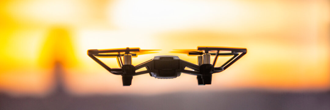 Drone flying outside in sky sunset banner panorama. Closeup of drone quadcopter with security camera outdoor.