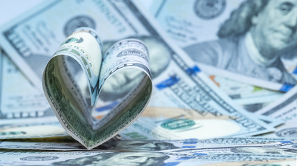 One hundred dollars US banknote in the shape of a heart. Money background. Concept financial love and a gift for Valentine's Day. Copy space.