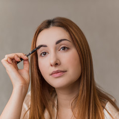 Brow Care. Closeup Of Beautiful Female Model Applying Brow Gel For Eyebrows. Portrait Young Woman. Beauty cosmetics Concept. 