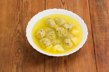 Chicken meatballs soup in white bowl on old rustic table