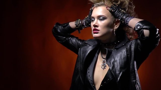 Girl in a black leather jacket, posing and holding her hair, punk rocker woman