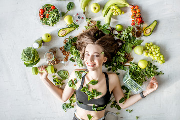 Beauty portrait of a sports woman surrounded by various healthy food lying on the floor. Healthy...