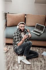Obraz premium Pleasant emotional man looking at his smartphone screen