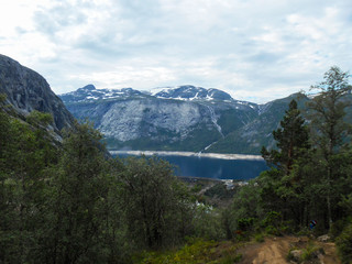 Popular tourist attraction near Trolltunga in sunny weather. View from the Trolltunga trail. Mountain lake Ringedalsvatnet. Norwegian landscape in sunny weather