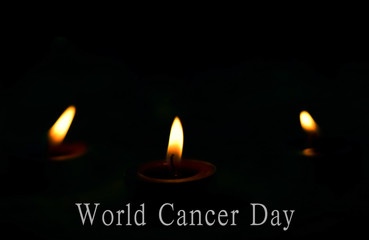 World Cancer Day concept: the candles burn brightly on the dark background