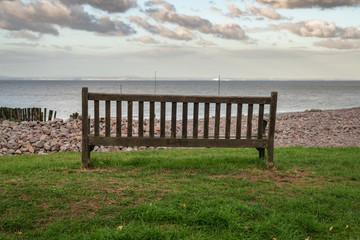 Fototapeta na wymiar A bench on the beach in Porlock Weir, Somerset, England, UK - looking at the Bristol channel