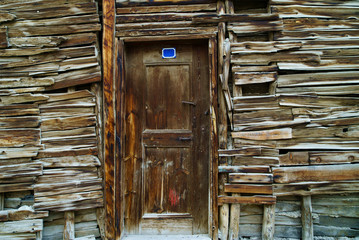old wooden plank door in a brown wooden wall too of a last century building, wooden texture