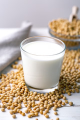 Raw soy seeds and glass of milk on slate background. Organic farming