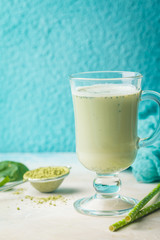 Green tea matcha latte in a glass cup on blue background. Concept of a healthy diet, superfood, antioxidant, cleansing