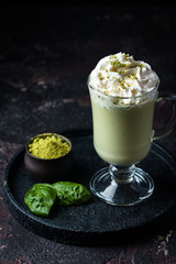 Green tea matcha latte in a glass cup on black background. Concept of a healthy diet, superfood, antioxidant, cleansing