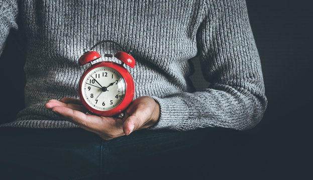 Time and life concepts with young man holding alarm clock and sitting on sofa.Motivation images