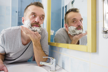 Guy shaving his beard in bathroom