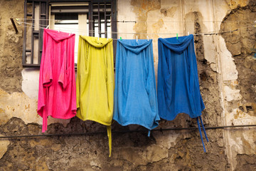 Colored clothes on clothesline against the old wall of house