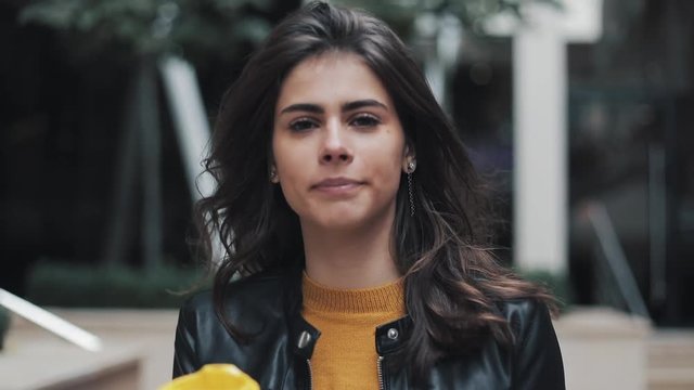 Young beautiful woman drinking coffee and walking on the street near business centre