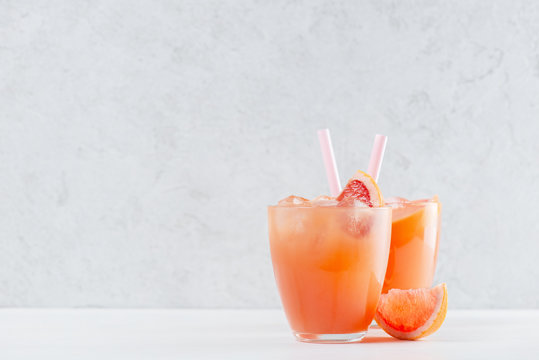Two glasses of fresh grapefruit juice on the white table