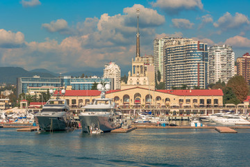 Sea port in summer. Many different yachts and boats stand at the marina. Yachtsmen and travelers are preparing to sail in the sea. In the background of the building of the seaside city.