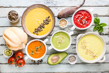 Variety of different colorful vegetable cream soups in a bowls, top view. Concept of healthy eating or vegetarian food.