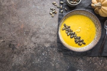 Seasonal autumn food. Healthy Pumpkin soup with cream and organic pumpkin seeds. Top view