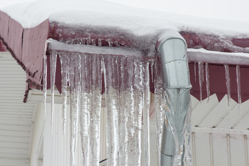 Icicles on the drain pipe,icicles on the roofs of the building. snow on the drain pipe