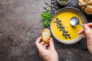 Seasonal autumn food. Healthy Pumpkin soup with cream and organic pumpkin seeds. Top view