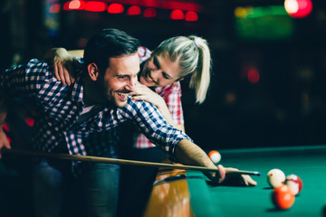 Young couple playing snooker together in bar