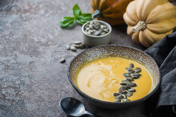 Seasonal autumn food. Healthy Pumpkin soup with cream and organic pumpkin seeds.