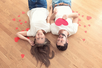 Fototapeta na wymiar Funny couple in love lying on the wood floor and laugh.