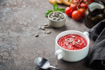 Healthy tomato soup in a white bowl with cream and sunflover seeds